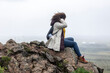 © ezellhphotography - mixed race African American  woman is sitting on a mountain  edge enjoying the inspiring view from the top. the black woman is enjoying her freedom to explore the Iceland adventure
