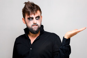 Wall Mural - a man with a beard and undead makeup on Halloween holds his hands in front of him