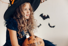 Little Girl Dressed As A Witch With A Pumpkin. Halloween. Pumpkin For Halloween