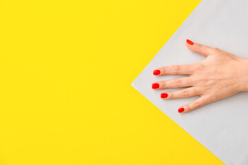 Female hand with beautiful manicure on yellow background, closeup