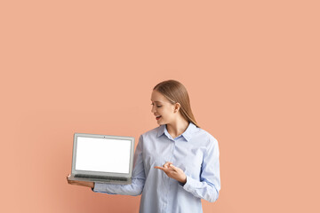 Beautiful young woman holding laptop with blank screen on color background