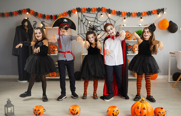 Wall Mural - Group of children having fun and doing zombie dance at Halloween party at home. Bunch of happy kids dressed up in different spooky costumes walking and dancing like zombies in decorated living room