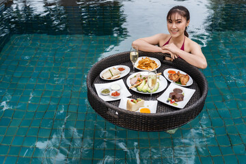 Wall Mural - cheerful woman enjoying with floating food in swimming pool