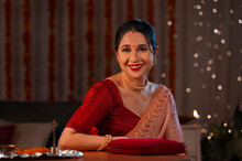 A Beautiful Woman Sitting With A Closed Jewellery Box And Smiling Amidst Diwali Decoration, Lights And A Pooja Thali.