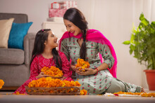 Mother And Daughter Holding Marigold Flowers In Their Hands While Decorating Home On Festival