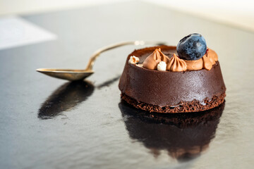 Chocolate dessert (fondant) with blueberry and cream and spoon.