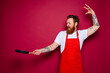 angry chef with beard and red apron cooks with pan