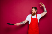 Angry Chef With Beard And Red Apron Cooks With Pan