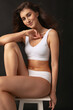 © master1305 - Studio shot of young beautiful pretty girl in lingerie sitting on high chair isolated over dark studio background. Natural beauty concept.