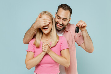 Young couple two friend family man woman in casual clothes together make surprise gift car key close eyes isolated on pastel plain light blue color background studio portrait People lifestyle concept