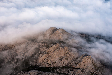 Wall Mural - View from above, stunning aerial view of a granitic massif surrounded by white, fluffy clouds during a beautiful sunrise. Mount Limbara (Monte Limbara) Sardinia, Italy.