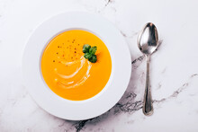 Flat Lay Of Pumpkin Soup On White Background With Cream And Mint Garnish