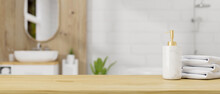 Wooden Table Top With Ceramic Shampoo Bottle And Towels Over Bathroom Interior Background