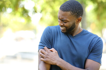 Black man scratching itchy arm in a park