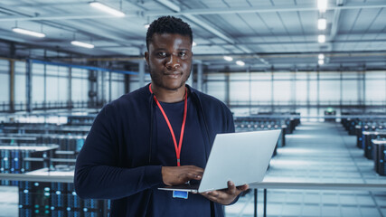 Leinwandbilder - Portrait of a Data Center Engineer Using Laptop Computer. Server Room Specialist Facility with African American Male System Administrator Working with Data Protection Network for Cyber Security.