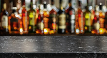 Grey Table Top And Beautiful Bokeh Shelves With Alcohol Bottles At The Background. Bar Concept.