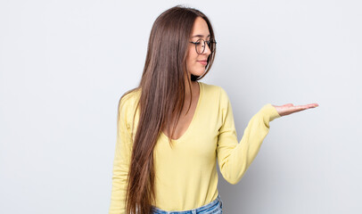 hispanic pretty woman feeling happy and smiling casually, looking to an object or concept held on the hand on the side