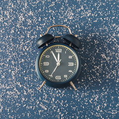Wall Mural - alarm clock over a cold blue background with scattered snow