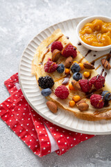 Wall Mural - Close up of crepes with berries and sauce on white plate