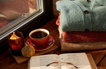 season and objects concept - open book with glasses, cup of coffee, autumn wool sweaters, pumpkin an
