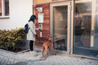 © Maskot - Woman entering password to open door while standing with dog at entrance of apartment