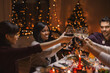 © Syda Productions - holidays, party and celebration concept - multiethnic group of happy friends having christmas dinner at home and drinking wine