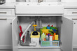 © New Africa - Open under sink cabinet with different cleaning supplies in kitchen