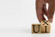© Mdisk - A wooden cube on a white table with text UI, UX. Concept of development and design and development, user interface, user experience, software, app. Copy space on left for a design, White background.