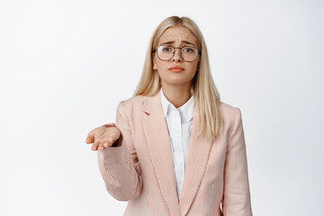 Wall Mural - Sad poor corporate woman, saleswoman raising empty hand, begging for money with miserable face expression, standing in suit and glasses over white background