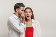 © Anastasia - Image of handsome young man whispering secret or interesting gossip to shocked beautiful woman in her ear isolated over white background