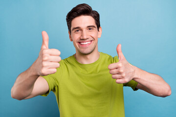 Sticker - Photo of funny young brunet guy thumb up wear green t-shirt isolated on blue color background