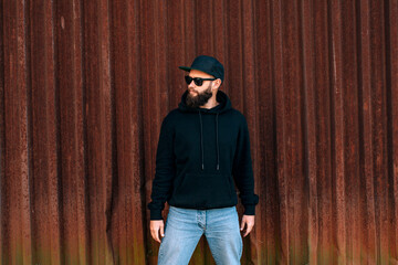 Wall Mural - City portrait of handsome hipster guy wearing black blank hoodie with space for your logo or design. Mockup for print. Hoodie template