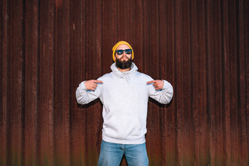 City portrait of handsome hipster guy with beard wearing gray blank hoodie with space for your logo or design. Mockup for print. Hoodie template