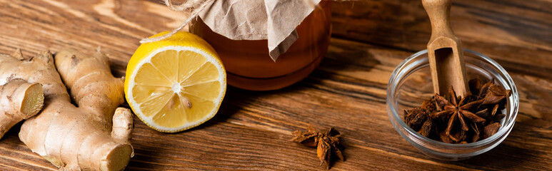 Poster - honey jar, juicy lemon, ginger root and jar with anise seeds and scoop on wooden table, banner