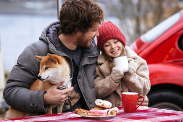 Loving dad spend winter holidays having picnic outdoor with cute little daughter and dog. Daddy and child drinking hot tea or cocoa travelling by car on Christmas vacation. Fatherhood and love concept