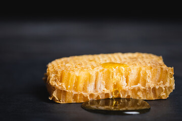 Wall Mural - close up view of honeycomb with golden honey on dark surface isolated on black