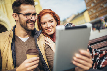 Wall Mural - Trendy young couple in town using tablet