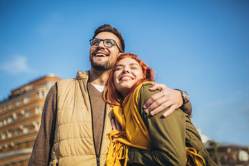 Wall Mural - Smiling couple enjoying on vacation, young tourist having fun walking and exploring city street during the day.