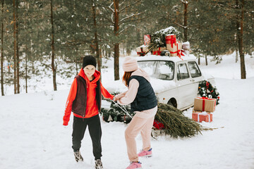 Children boy and girl with a dog stay near a retro car decorated for Christmas among the winter forest in the village and having fun with sledge, concept of family Christmas and winter holidays