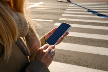 Wall Mural - woman looks at a smartphone while crossing the road. the pedestrian does not follow the road rules. 