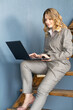 Happy middle-aged business woman sitting on stairs. Uses laptop for video chat.