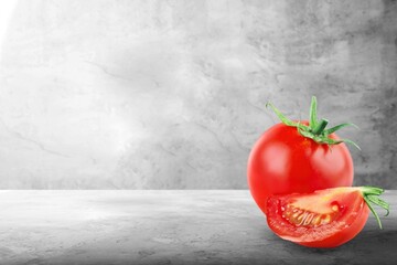 A whole red fresh tomato and slice on the desk