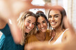 © Xavier Lorenzo - Three multiracial female friends taking selfie and making hand frame gesture in the street, looking through fingers at camera - Diverse young women having fun on vacation - Millennial people concept