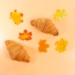 two croissant with autumn leaves on orange background