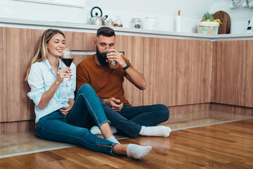 Beautiful couple drinking wine in the kitchen at home