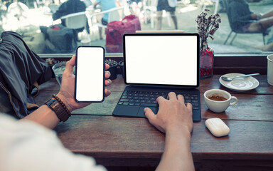 Wall Mural - Cropped shot of man hand working on mobile and tablet at cafe.