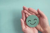 Fototapeta  - Hands holding green happy smile face paper cut, good feedback rating,positive customer review, experience, satisfaction survey ,mental health assessment, child wellness,world mental health day concept