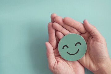 Wall Mural - Hands holding green happy smile face paper cut, good feedback rating,positive customer review, experience, satisfaction survey ,mental health assessment, child wellness,world mental health day concept