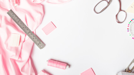 sewing business. Tailor's workplace with threads, scissors, spools, pink fabric. white background top view space for text in the frame. Tailoring concept