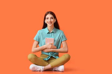 Canvas Print - Young woman with tablet computer listening to audiobook on color background